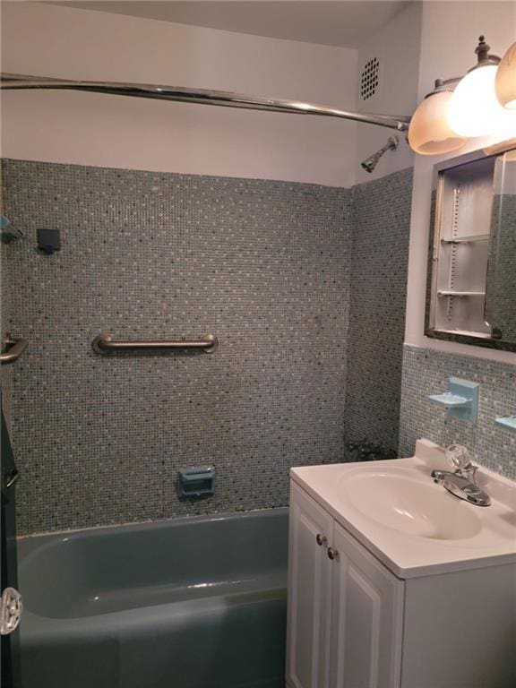 bathroom featuring decorative backsplash, vanity, tile walls, and tiled shower / bath combo