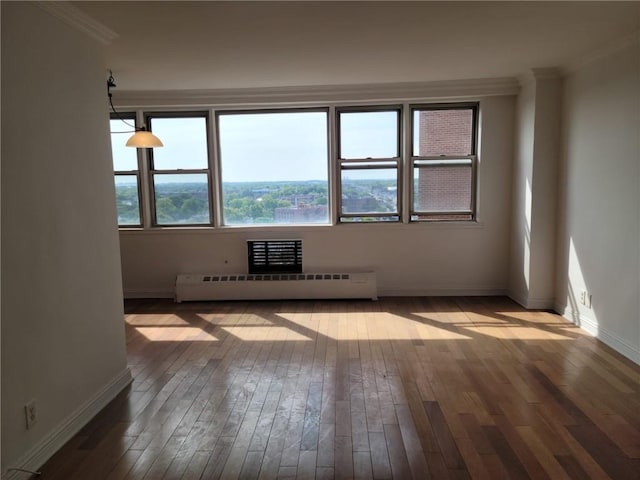 empty room featuring crown molding, hardwood / wood-style floors, and baseboard heating