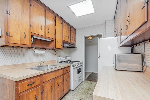 2630 Cropsey Ave Unit 9K, Brooklyn, NY 11214 - kitchen featuring white gas range, a sink, under cabinet range hood, light countertops, and brown cabinets