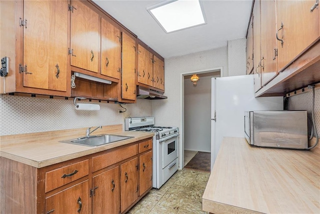 kitchen featuring light countertops, white appliances, a sink, and under cabinet range hood