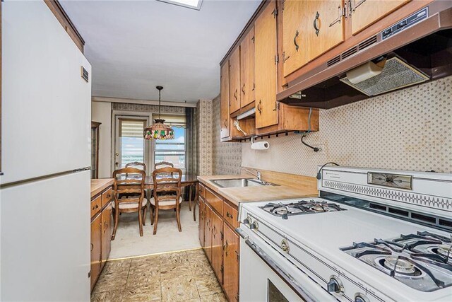 kitchen with hanging light fixtures, sink, and white appliances