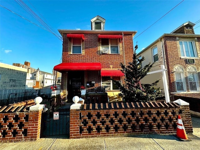 view of front facade with a gate, brick siding, and fence