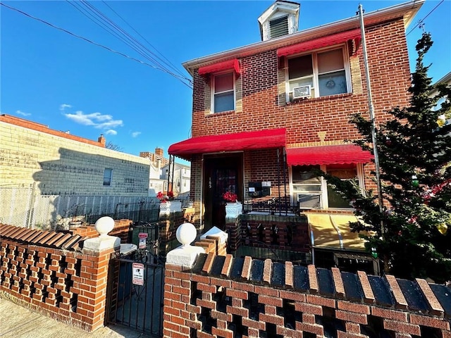 view of front facade with a gate, brick siding, and fence