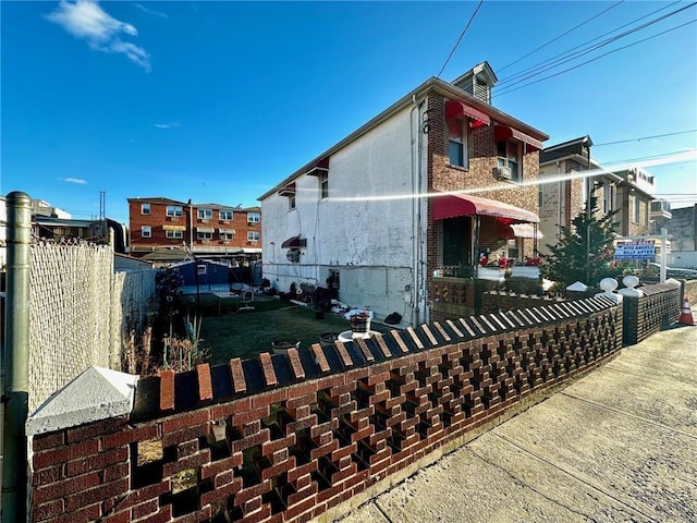 view of side of home featuring fence and brick siding