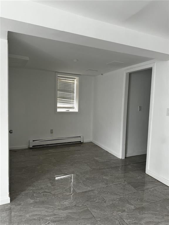 unfurnished room featuring marble finish floor, baseboard heating, and baseboards