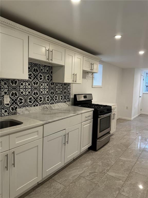 kitchen with white cabinets, light stone countertops, sink, and stainless steel gas stove