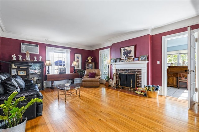 living room featuring a fireplace, wood-type flooring, an AC wall unit, and ornamental molding