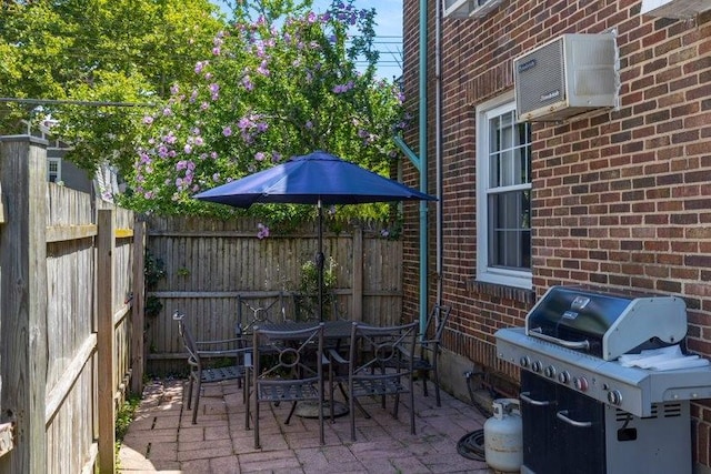 view of patio / terrace with a wall unit AC and a grill