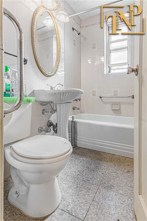 bathroom featuring washtub / shower combination, toilet, and tile walls