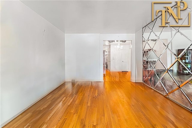 empty room featuring a chandelier and wood finished floors