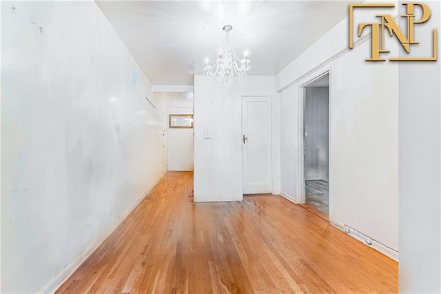 empty room with wood finished floors and a notable chandelier