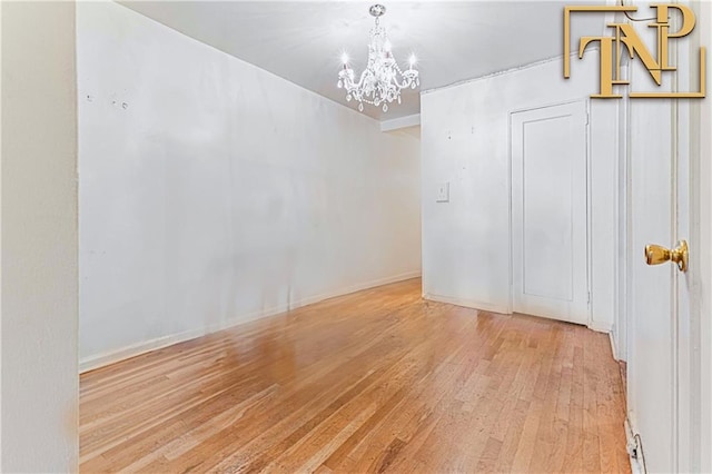 spare room featuring baseboards, a chandelier, and wood finished floors