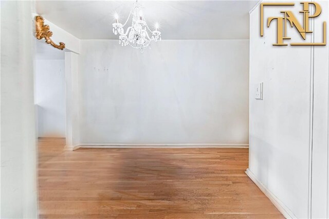 interior space featuring baseboards, wood finished floors, and a chandelier