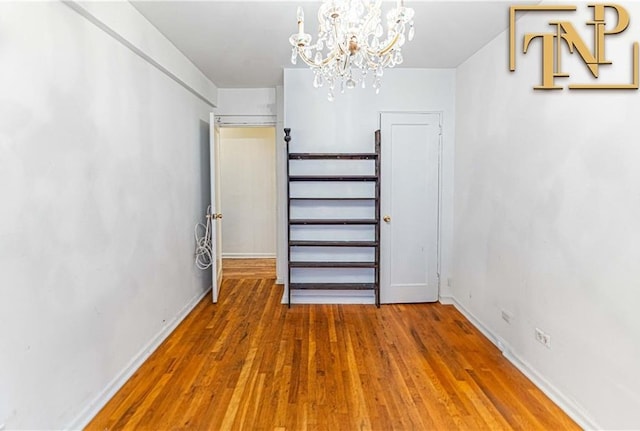 interior space featuring baseboards, a chandelier, and wood finished floors