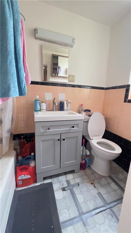 bathroom with tile walls, toilet, and vanity