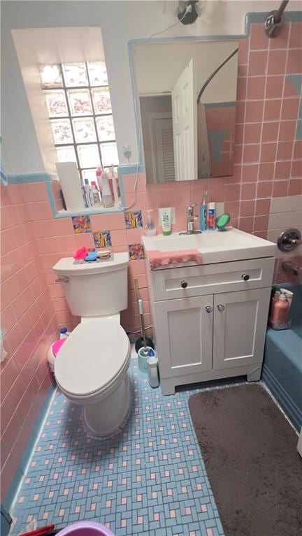 bathroom featuring toilet, tile walls, and vanity