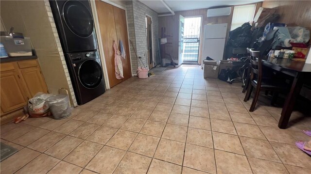 interior space featuring an AC wall unit, a baseboard heating unit, stacked washer and dryer, wood walls, and light tile patterned floors