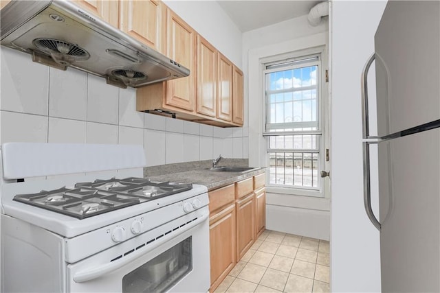 kitchen featuring stainless steel fridge, white gas range, a healthy amount of sunlight, and range hood