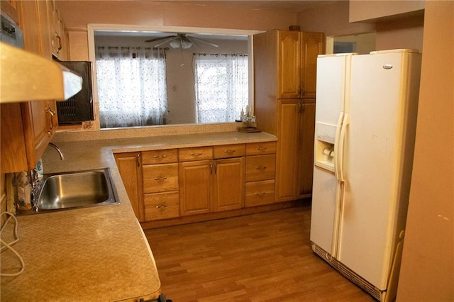 kitchen featuring ceiling fan, white fridge with ice dispenser, sink, kitchen peninsula, and light hardwood / wood-style floors