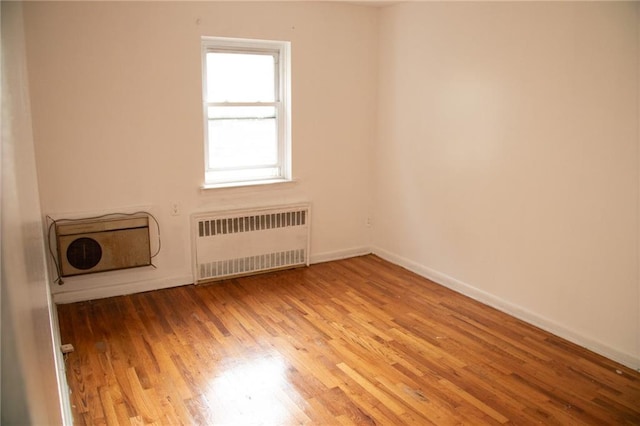 spare room featuring radiator heating unit and light wood-type flooring