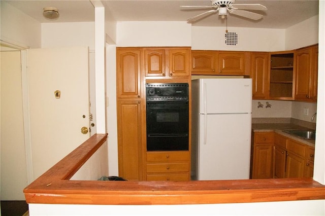 kitchen with white refrigerator, double oven, ceiling fan, and sink