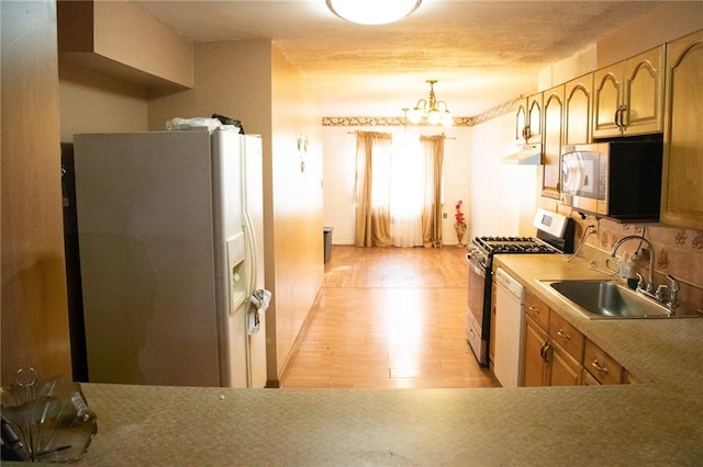 kitchen with sink, an inviting chandelier, light hardwood / wood-style flooring, backsplash, and appliances with stainless steel finishes