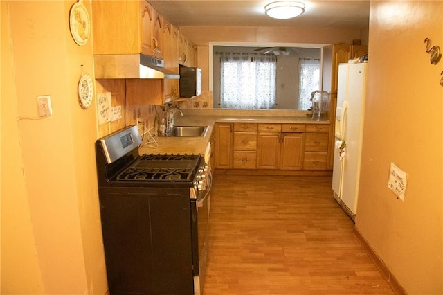 kitchen featuring stainless steel range with gas cooktop, sink, white fridge with ice dispenser, and light wood-type flooring