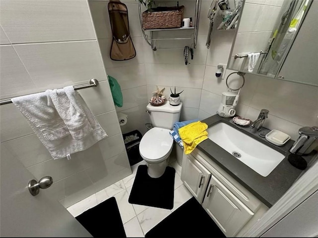 bathroom with vanity, tile walls, and toilet