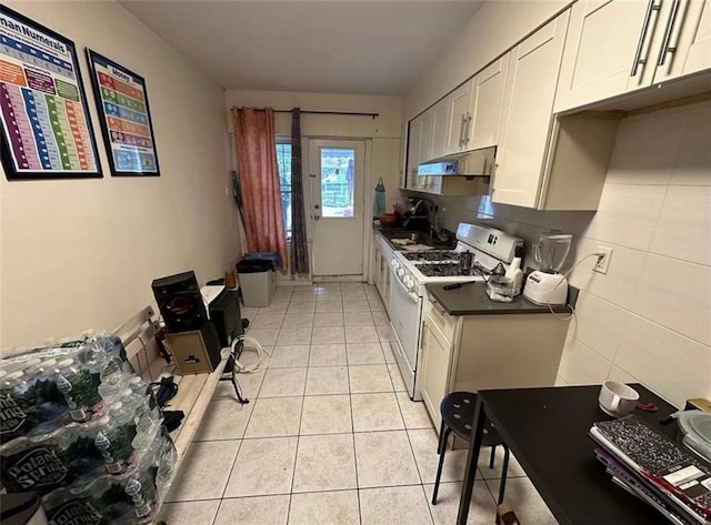 kitchen with sink, light tile patterned floors, gas range gas stove, backsplash, and white cabinets