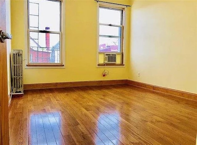 unfurnished room featuring radiator, cooling unit, and hardwood / wood-style floors