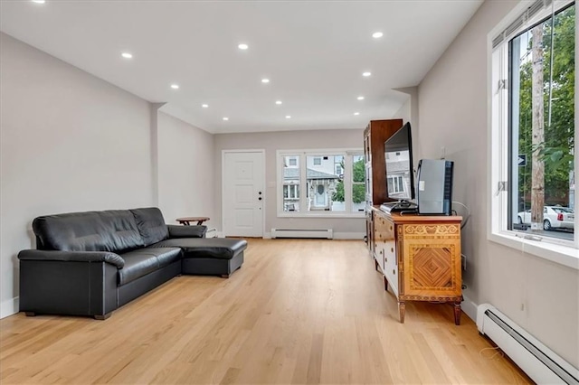 living room with a baseboard heating unit, light hardwood / wood-style flooring, and a healthy amount of sunlight