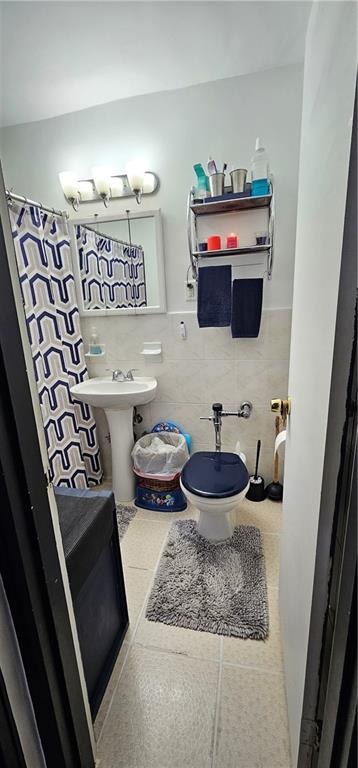 full bath featuring tile walls, a shower with curtain, toilet, a sink, and tile patterned flooring