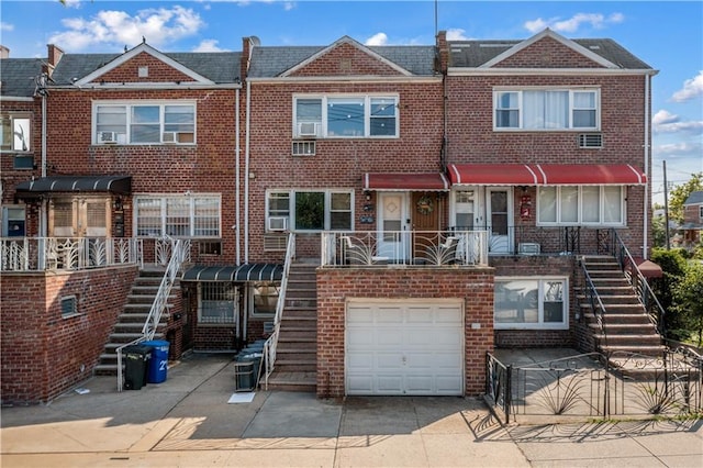 multi unit property with brick siding, a garage, and stairway