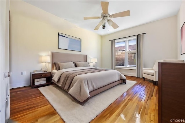 bedroom with a ceiling fan, baseboards, and light wood-style floors