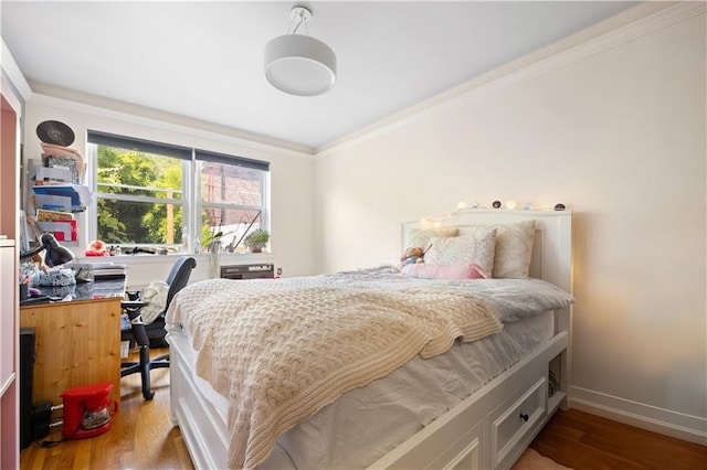bedroom featuring crown molding, baseboards, and wood finished floors