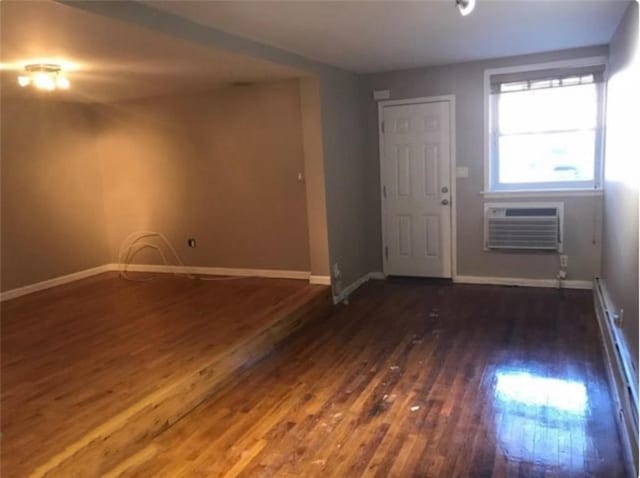 foyer entrance with baseboards, a wall unit AC, wood finished floors, and a baseboard radiator