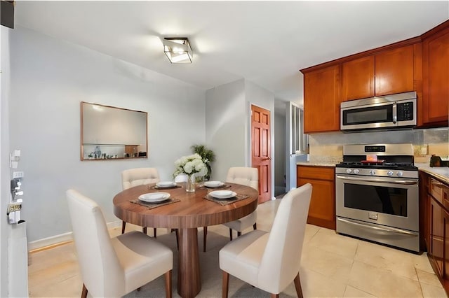 kitchen featuring baseboards, appliances with stainless steel finishes, and brown cabinets