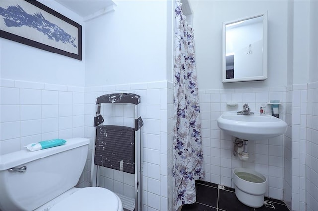 bathroom featuring tile walls, toilet, wainscoting, a shower with shower curtain, and tile patterned floors