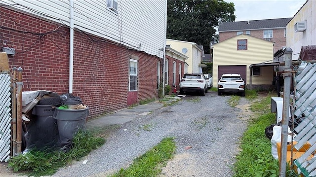 view of side of property with a garage, brick siding, a wall mounted air conditioner, and driveway