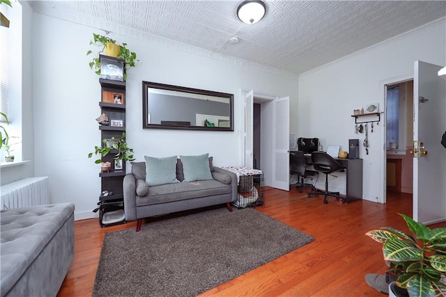 living area with radiator heating unit, a desk, and wood finished floors