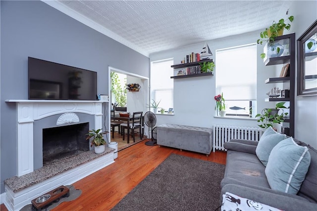 living room with radiator heating unit, wood finished floors, a high end fireplace, and an ornate ceiling