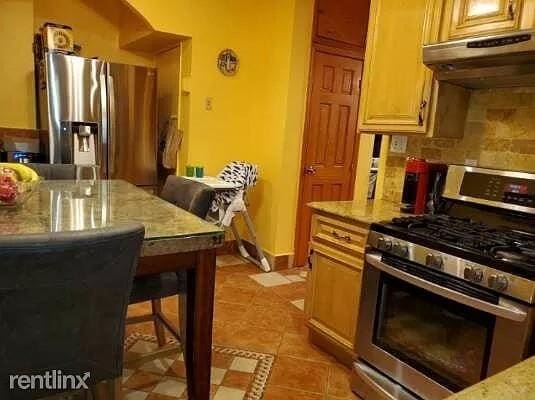 kitchen with backsplash, a kitchen breakfast bar, light tile patterned floors, stainless steel appliances, and light stone countertops