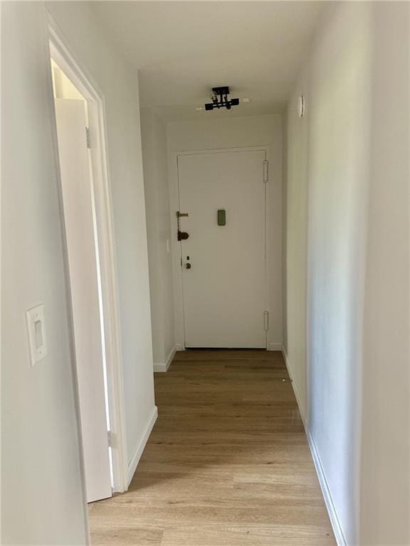 hallway featuring light wood-style flooring and baseboards