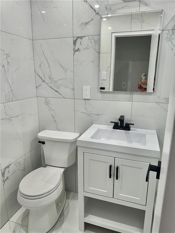 bathroom with vanity, tile walls, and toilet