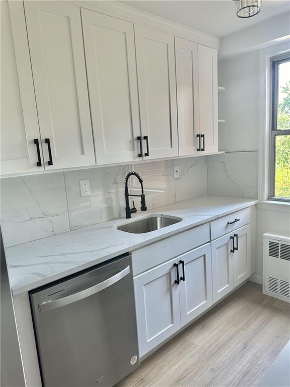 kitchen with tasteful backsplash, stainless steel dishwasher, sink, and white cabinets