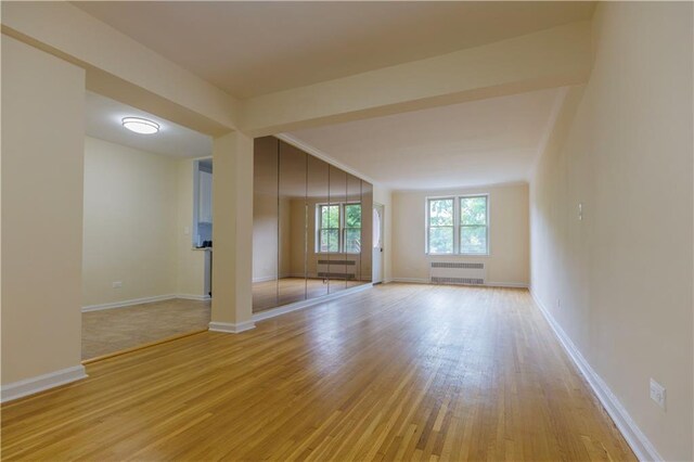 spare room featuring radiator heating unit and light hardwood / wood-style floors