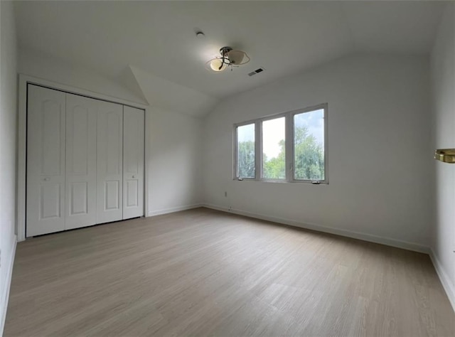 unfurnished bedroom with a closet, lofted ceiling, and light hardwood / wood-style floors