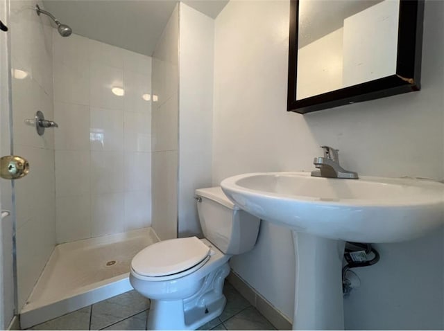 bathroom featuring tiled shower, toilet, and tile patterned floors