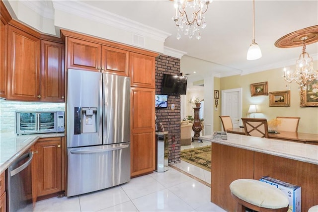 kitchen featuring light stone counters, a notable chandelier, appliances with stainless steel finishes, and hanging light fixtures