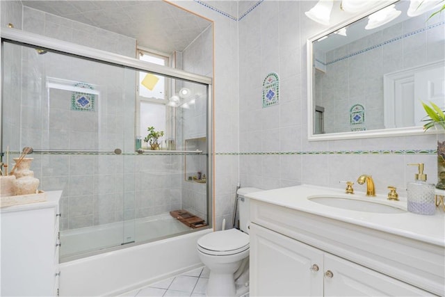 full bathroom featuring vanity, toilet, tile patterned floors, tile walls, and combined bath / shower with glass door